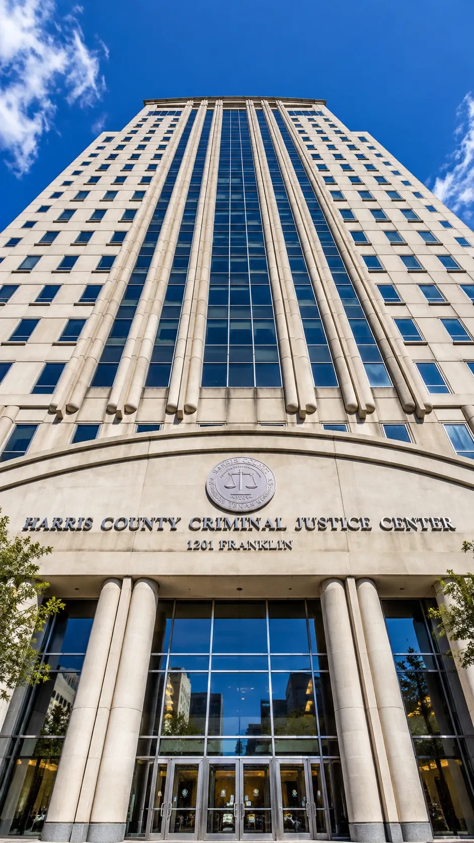 Harris County Criminal Justice Center at 1201 Franklin St in downtown Houston, looking up at the tower against a blue sky